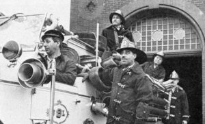 Firefighters in gear standing on fire truck